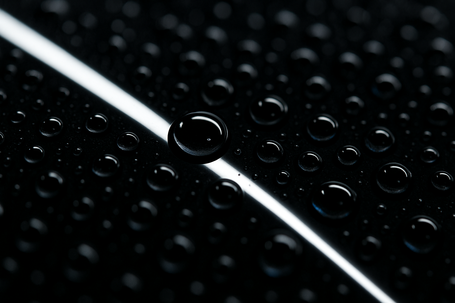 Macro shot of tight water beads sitting on ceramic-coated black paint